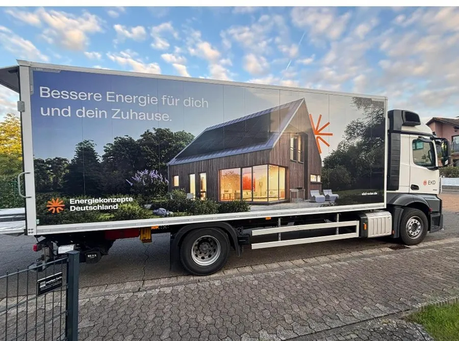 Ein weißer Lastwagen mit Haus-Motiv auf der Plane