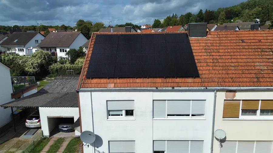 Dach eines weißen Hauses mit schwarzen Solarmodulen